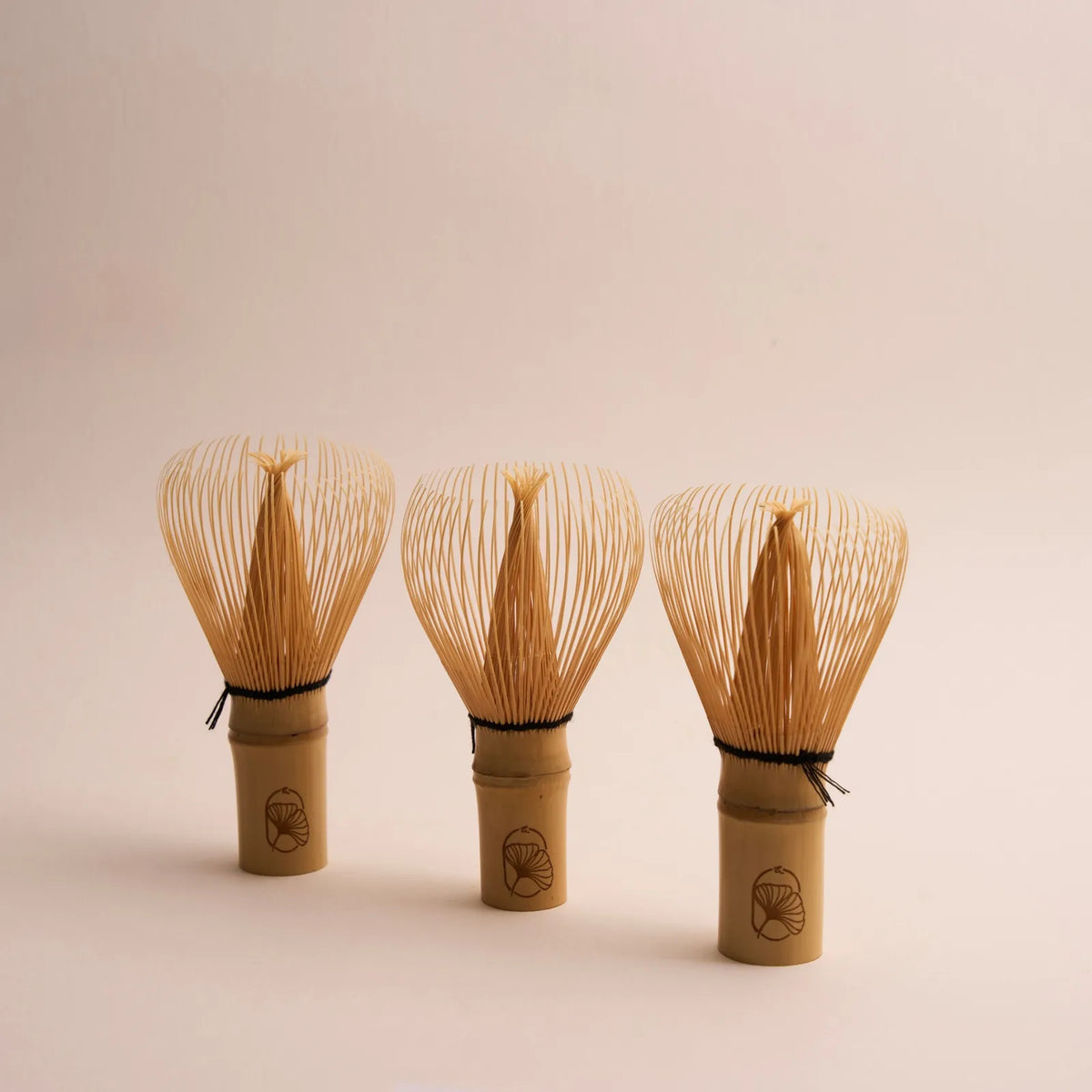 Three bamboo whisks on a pink ground