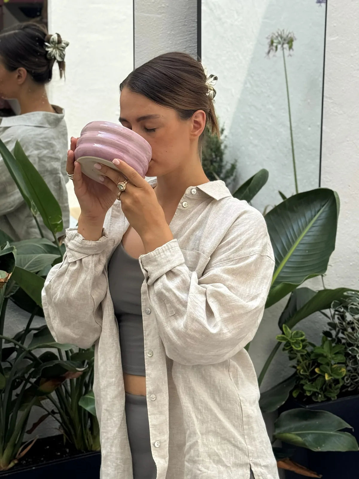 A woman drinking matcha from a pink bowl