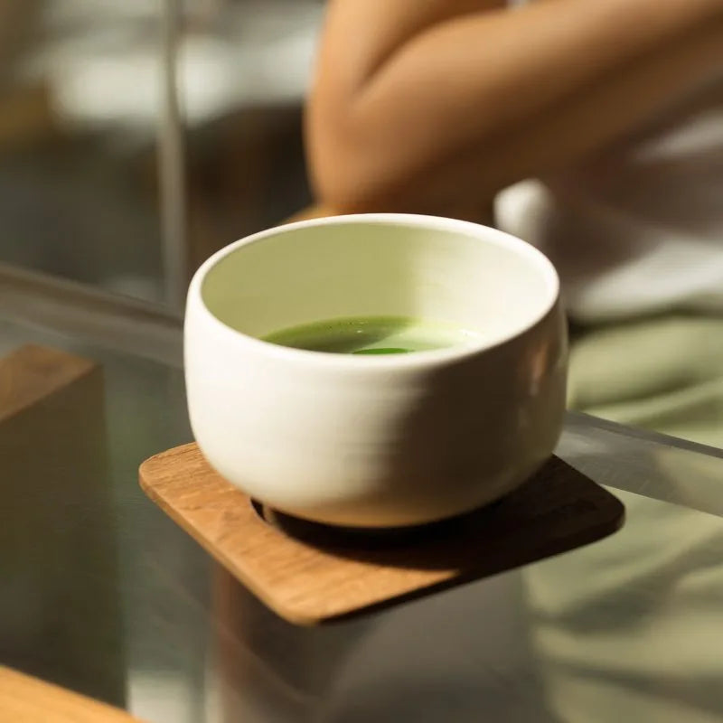 A cup of matcha on a wooden coaster