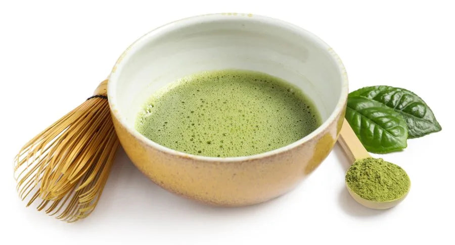A bowl of whisked matcha with a bamboo whisk and scoop