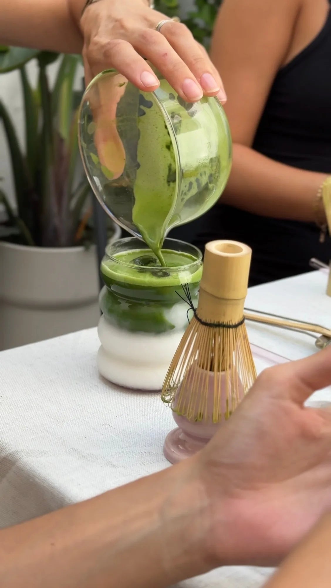 Pouring matcha into a glass at the pop-up bar, whisk beside it