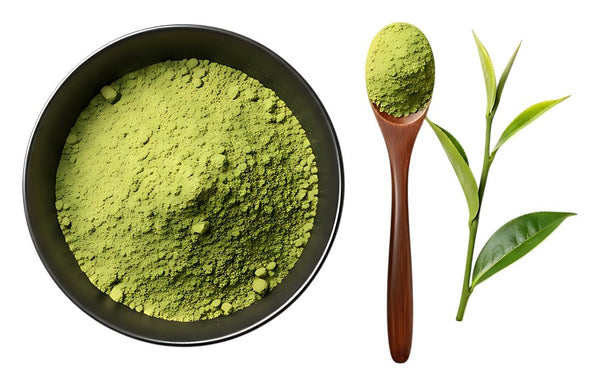 Matcha powder in a bowl, a spoonful and fresh tea leaves