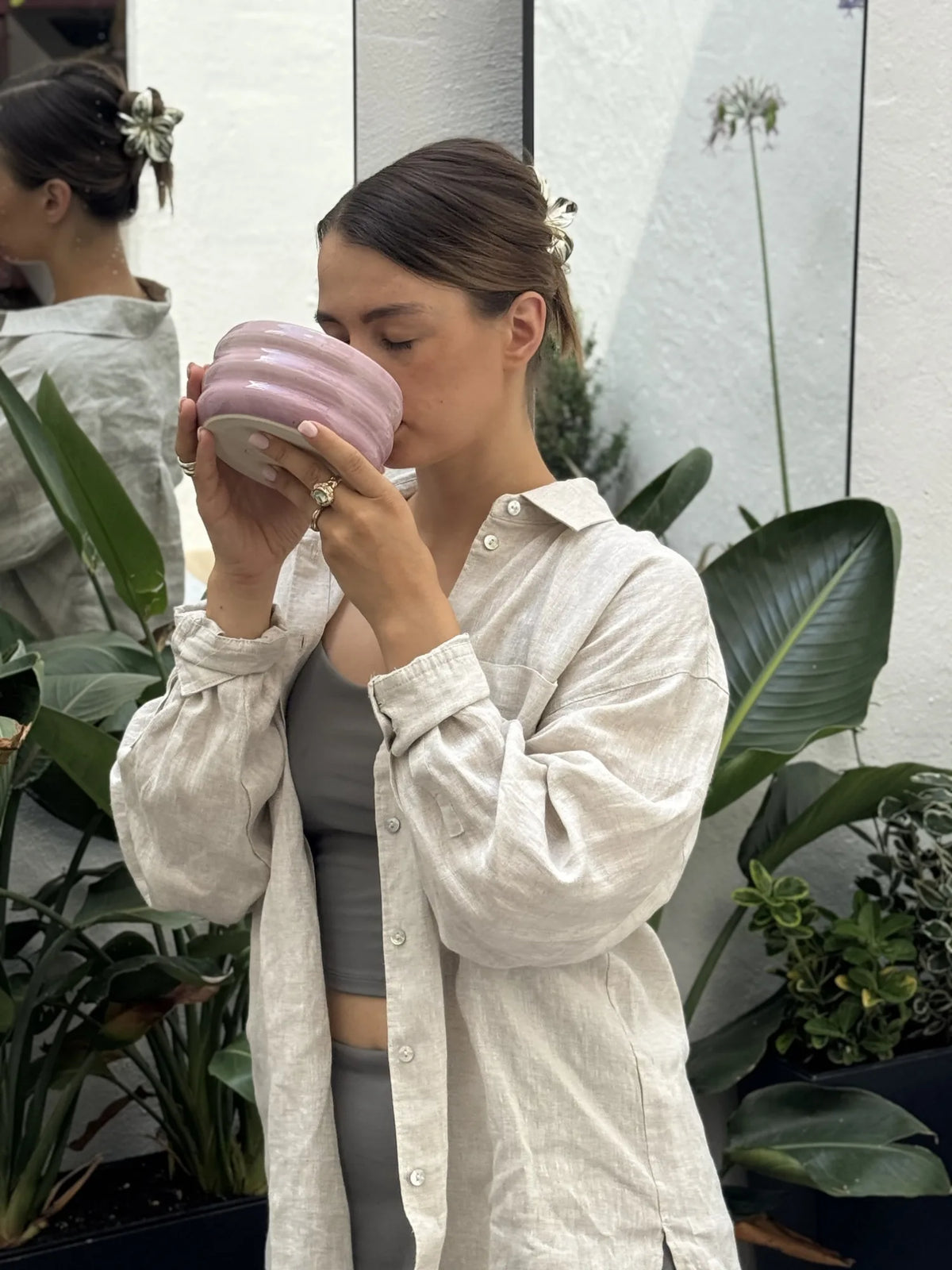 Sintija drinking from a pink bowl among plants