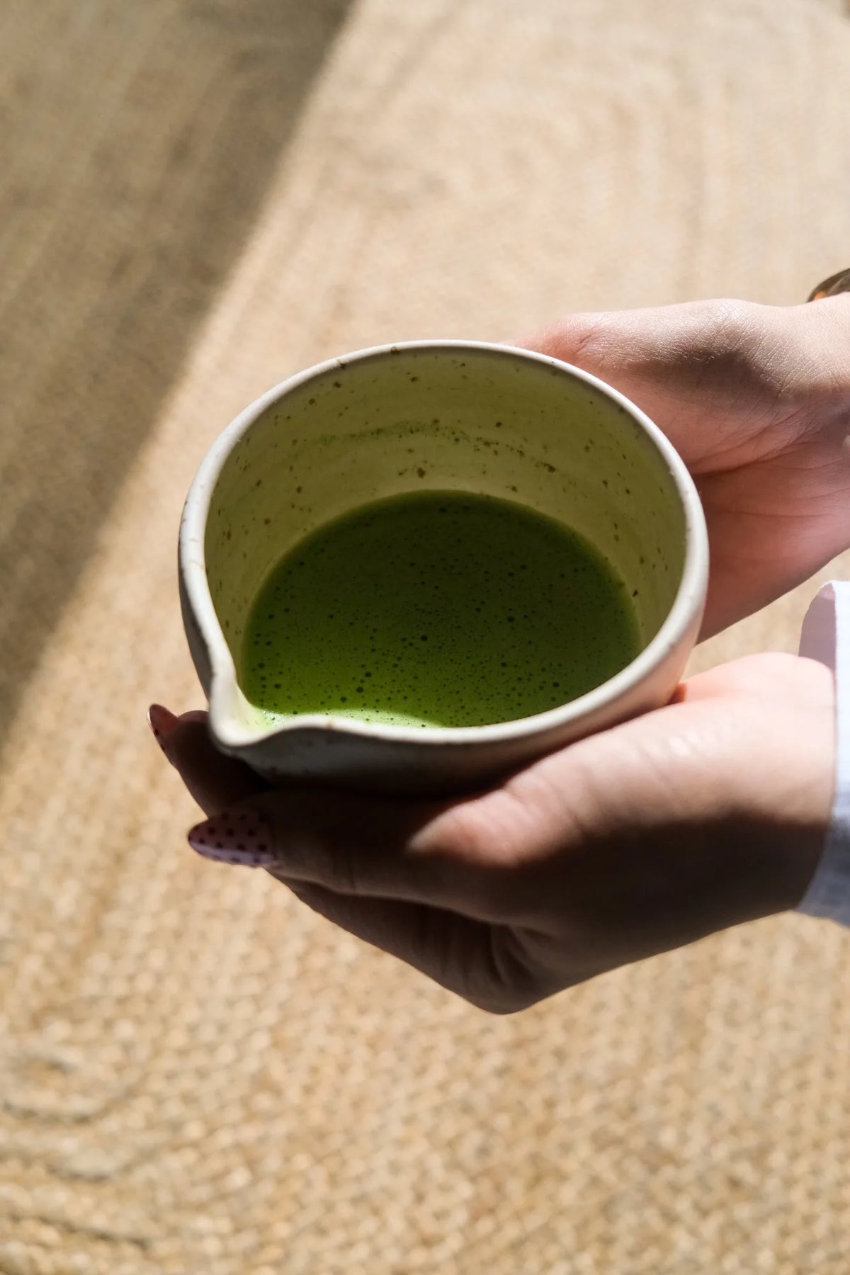 Hands holding a bowl of whisked matcha
